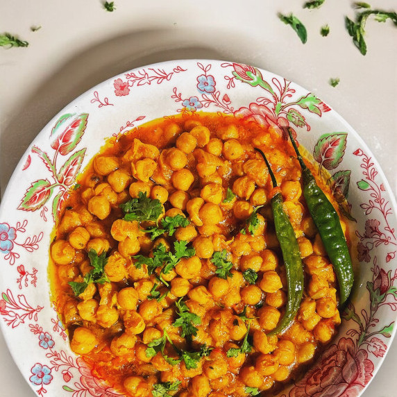 Chana masala arranged in floral bowl placed on marble countertop