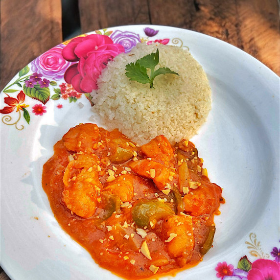 Chicken Manchurian arranged in a floral plate placed on wooden table