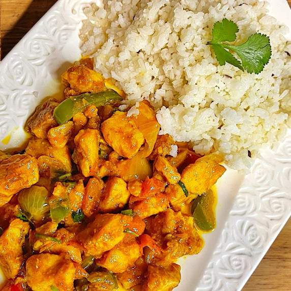 Chicken Jalfrezi arranged in white dish placed on wooden table