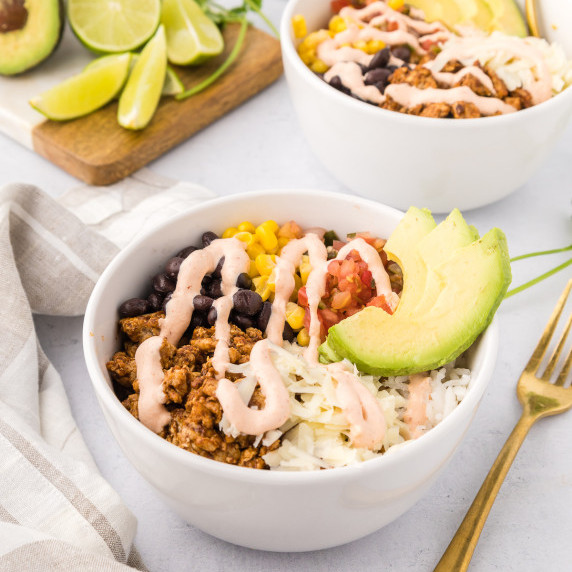 chicken burrito bowl in a white bowl served with avocados 