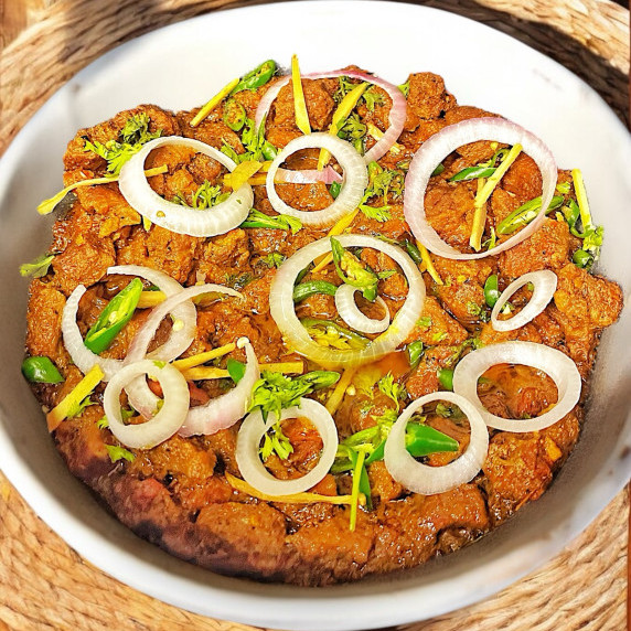 Beef masala arranged in white bowl placed on bamboo mat