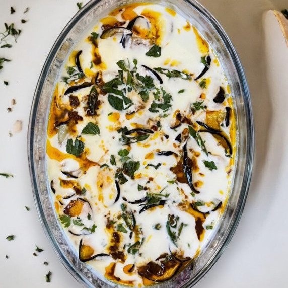 Yogurt eggplant curry arranged in Pyrex dish placed on marble countertop 