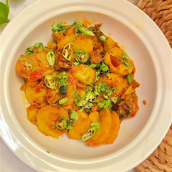 Aloo masala arranged in white bowl placed on marble countertop