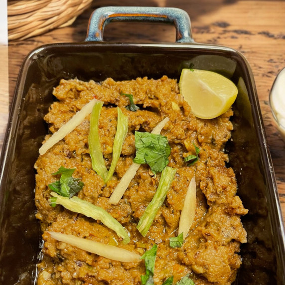 Dum ka keema arranged in black dish on a wooden table 