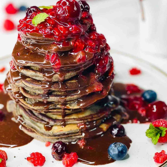 Stacked American Style Chocolate Berry Pancakes, garnished with berry sauce and chocolate ganache