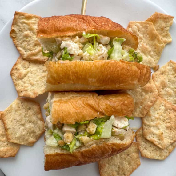 Overhead view of a chicken Caesar salad sandwich that’s been cut in half to show more of the filling