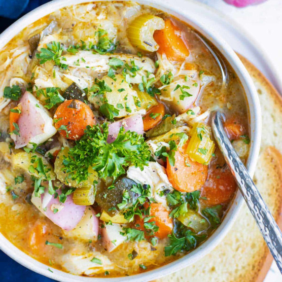 Instant Pot Chicken Vegetable Soup RECIPE served in a white soup bowl with bread on the side.