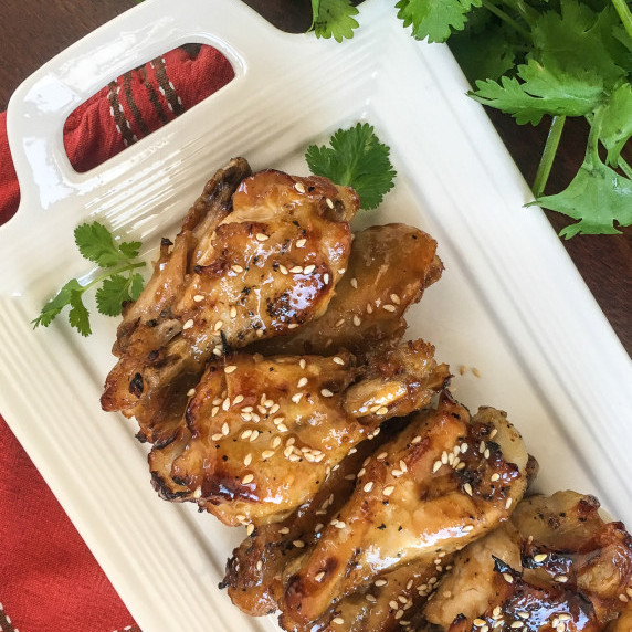 Honey Garlic Chicken Wings on a platter with fresh parsley as a garnish.