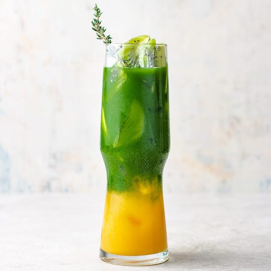 Iced matcha mango tea in a glass with rosemary sprig