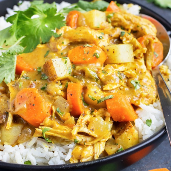 Instant Pot Yellow Chicken Curry RECIPE served over rice in a black bowl.