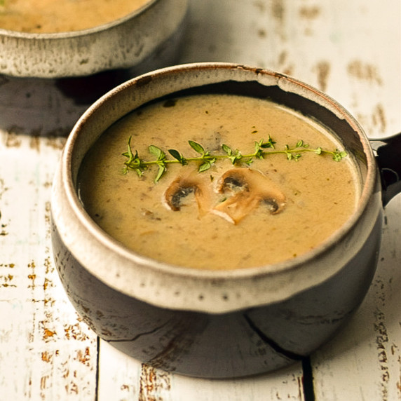 cream of mushroom soup in brown bowls on a white wooden background