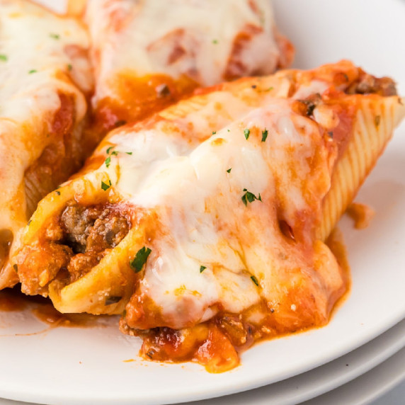 Close up stuffed shells with ground beef and cheese on a plate.