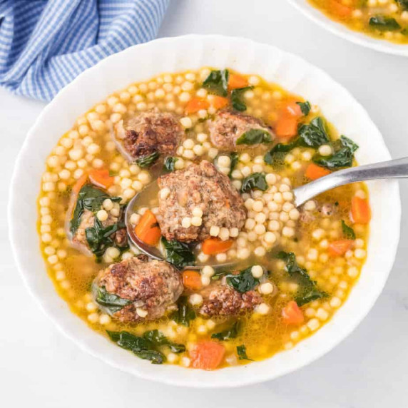 Bowl of Italian wedding soup on counter, full of meatballs, pasta and vegetables
