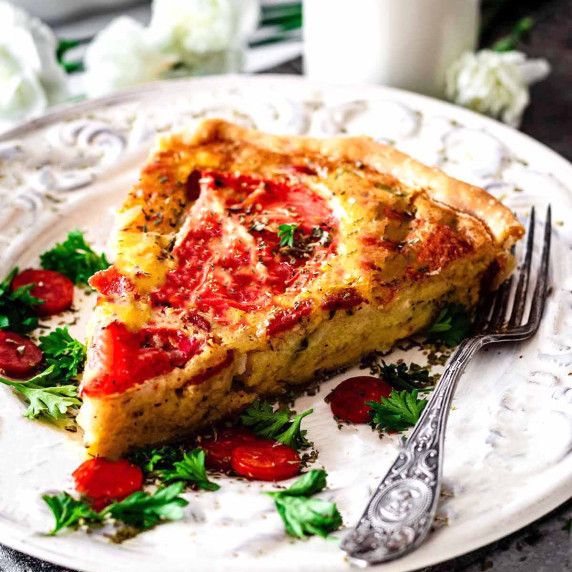 Italian quiche slice on a white plate with a silver fork.