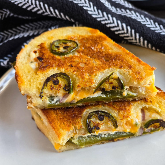 Golden brown bread with pops of green jalapeno against a black patterned towel.