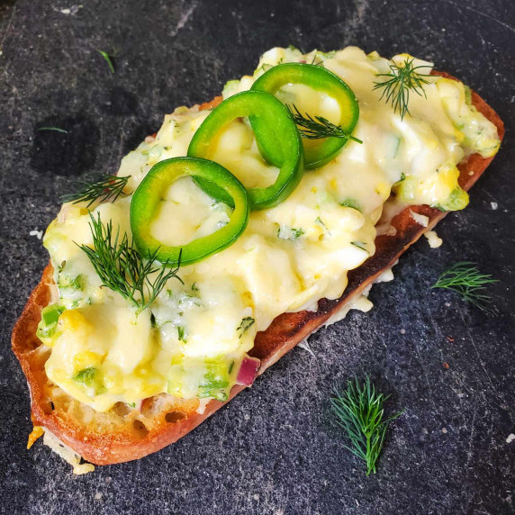 Golden sourdough topped with creamy egg salad with pops of green jalapeno and dill