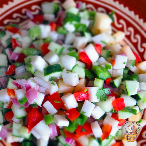 Jicama Salsa with apple, bell peppers, chili, and lime in a red and white bowl with a red napkin
