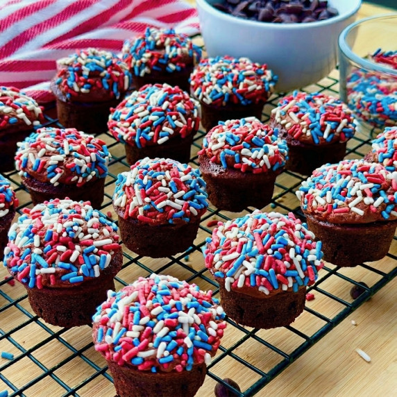brownie cupcakes with sprinkles on a rack with towel and chocolate chips 