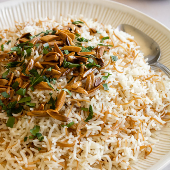 lebanese rice with toasted vermicellu garnished with toasted almonds and parsley with a spoon.