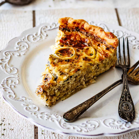 Slice of leek and mushroom quiche on a white plate with two forks