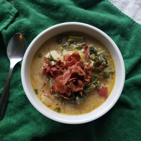 A soup with bacon on top in a white bowl on a bright green towel.
