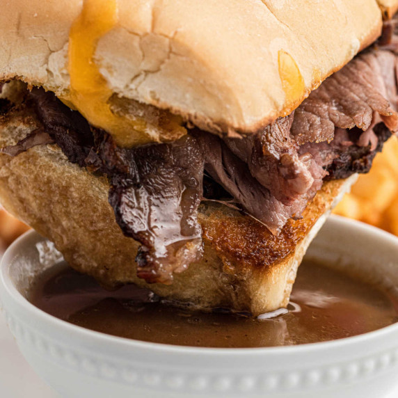 Close up of a prime rib sandwich being dipped into au jus.