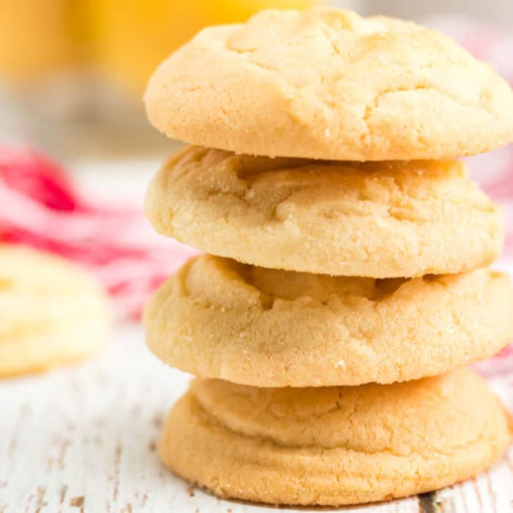 Four lemon sugar cookies are stacked on a counter.