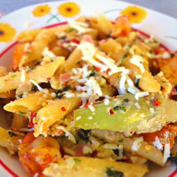 Lemon cilantra pasta topped with bell pepper, artichokes, and cheese in a white bowl
