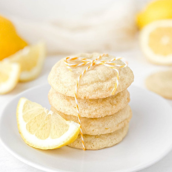 stack of lemon sugar cookies and a lemon wedge on a white plate