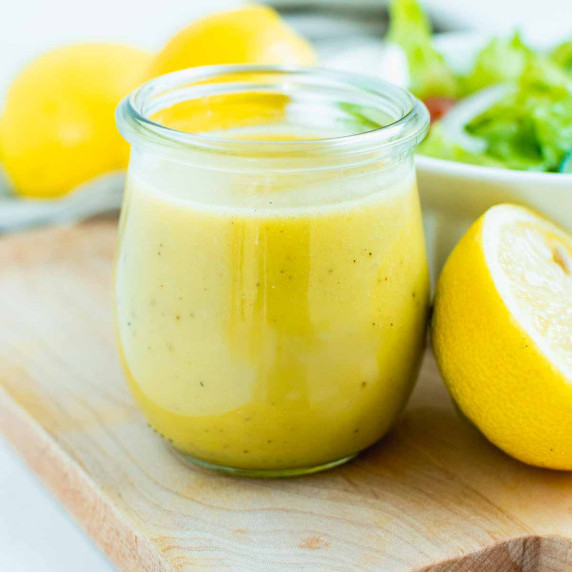 small batch of lemon vinaigrette in mason jar next to small salad.