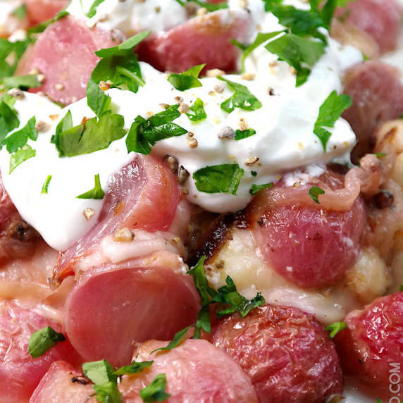 Pink colored roasted radishes topped with melted mozzarella, sour cream and fresh chopped parsley.