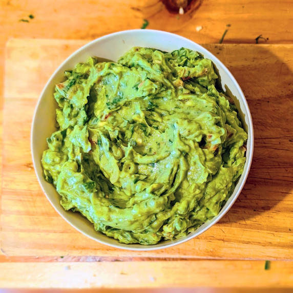 lime zest guacamole in a bowl on a wooden countertop