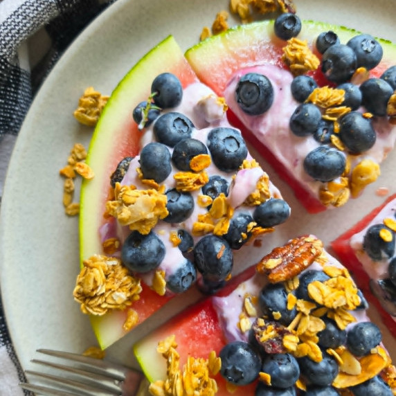 Watermelon topped with yogurt, blueberries, and crispy, golden granola.