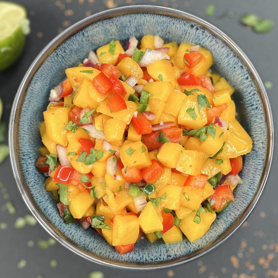 Mango salsa in a blue bowl on a gray countertop.