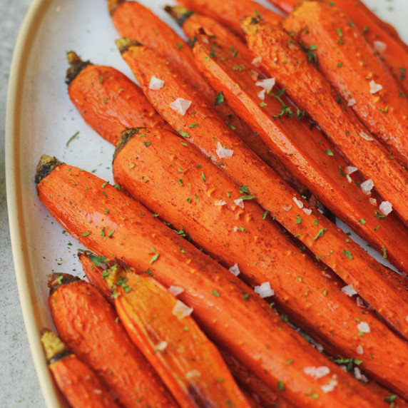 finished maple roasted carrots in a white bowl with a fork next to it