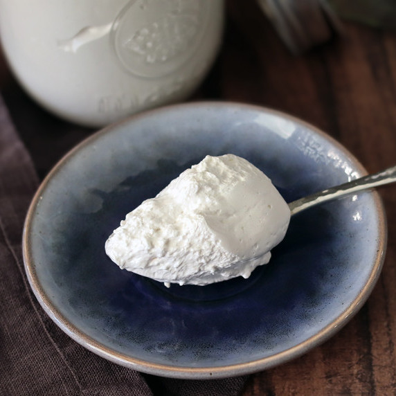 A spoonful of marshmallow crème on a small blue plate with a jar of crème in the background.