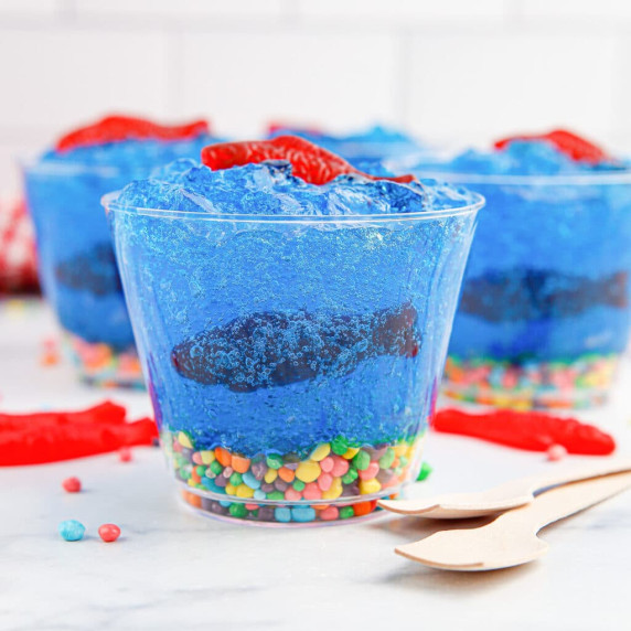 Cups filled with blue Jell-o, candy fish and candy rocks decorated to look like a fish tank.