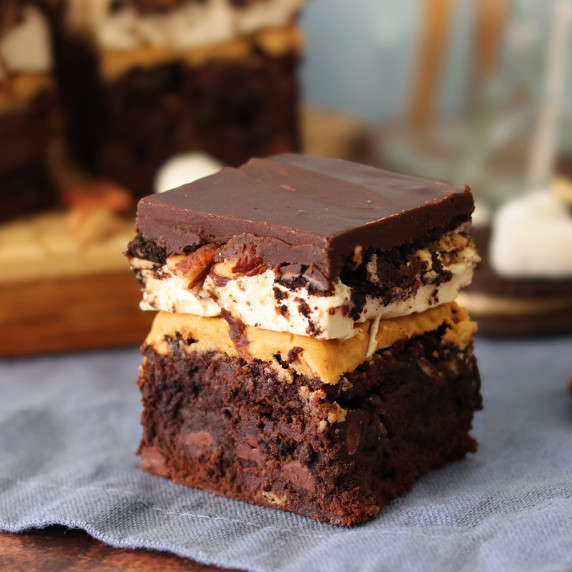 Peanut Butter Mississippi Mudpie Brownie on a blue napkin in front of a platter with more brownies.