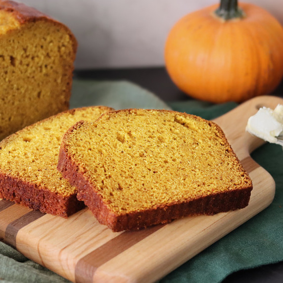Two slices of pumpkin bread on a wooden board.