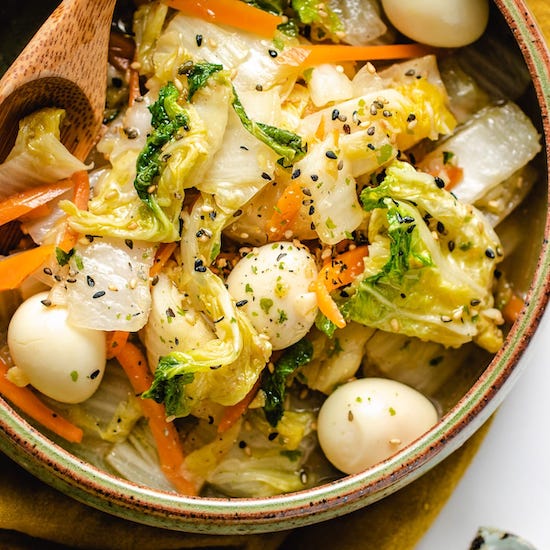 Napa cabbage, carrots, quail eggs and sesame seeds in a bowl