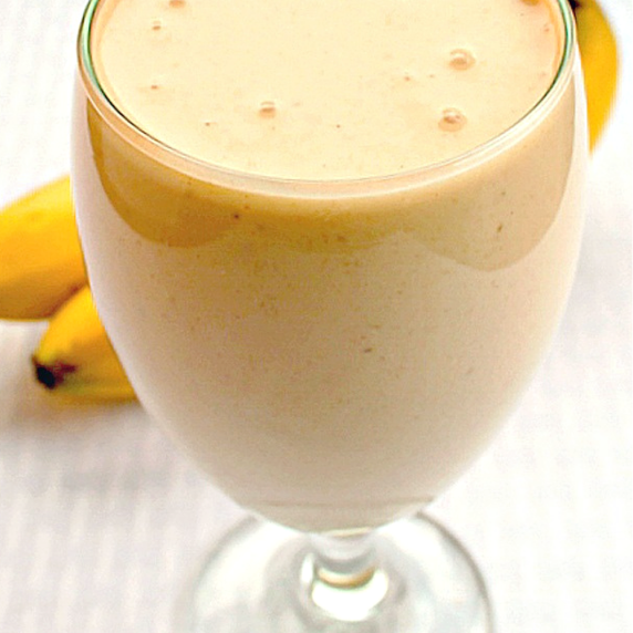 Glass goblet with Nutty Monkey Smoothie with bananas on table in background
