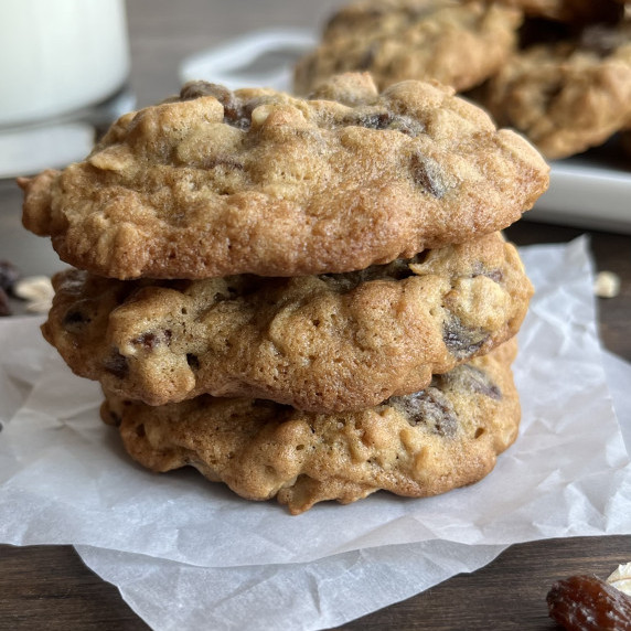 Oatmeal raisin cookies stacked on parchment paper.