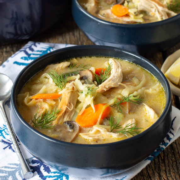 Blue bowl filled with One Pot Creamy Chicken and Cabbage Soup on a napkin with a spoon to the side.