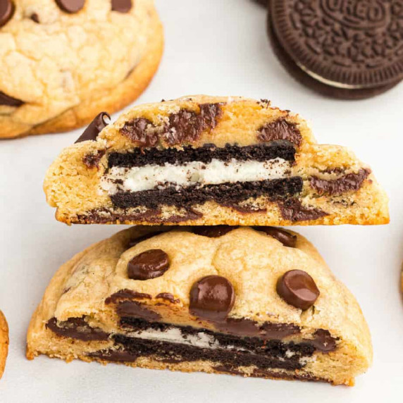 Up close view of a chocolate chip cookie cut in half showing an Oreo in the middle.