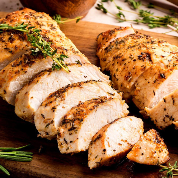 Sliced oven-roasted turkey tenderloins with herb crust on a wooden board, showing juicy interior.