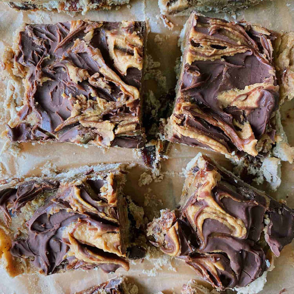 Squares of peanut butter and chocolate covered desserts not evenly sliced