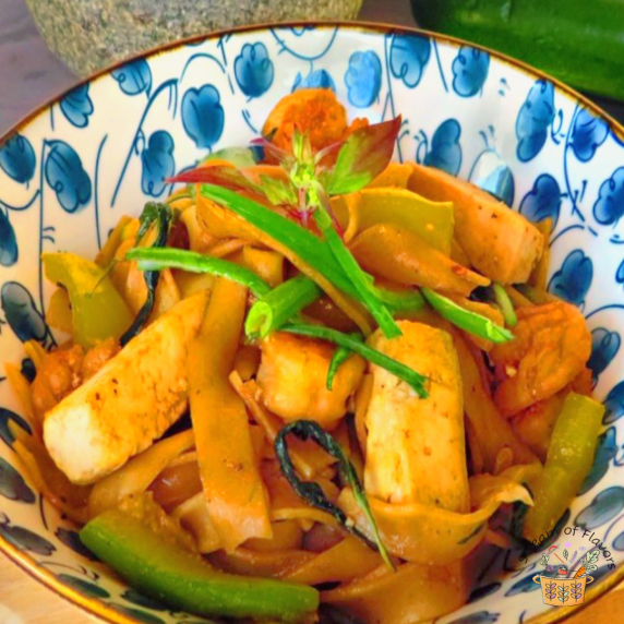 Pad Kee Mao with shrimp, vegetables, zucchini, and tofu in a blue and white bowl
