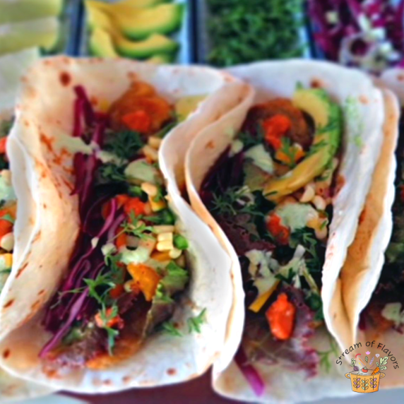 Tortillas filled with pan-fried fish fillets, corn salsa, salad, homemade taco sauce, cabbage slaw