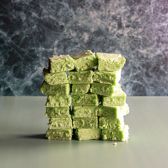 A stack of pandan fudge on a solid soft green and marble dark green backdrop.