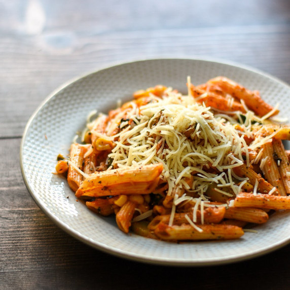 Pasta with vegetables and cheese on a plate.